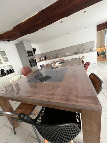 une grande table en bois dans une cuisine avec des chaises dans l'établissement With us , your home nous chez vous, à Bécon-les-Granits