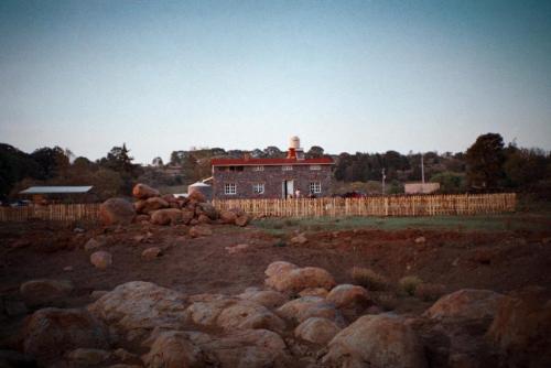 a house with a lighthouse behind a fence and rocks at Hermosa casa de campo a solo 90min de CDMX in San Lorenzo Octeyuco