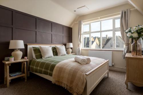 een slaapkamer met een bed en een groot raam bij Broadway Country Chic Cottage in Broadway