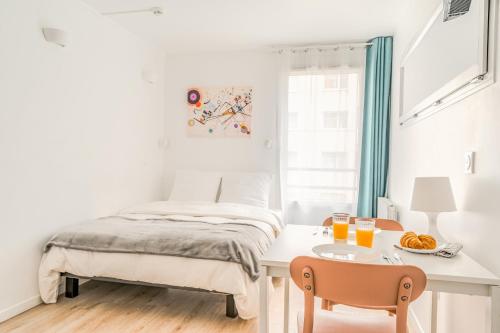 une chambre avec un lit, une table et des chaises dans l'établissement Résidence inner center Courbevoie, à Courbevoie