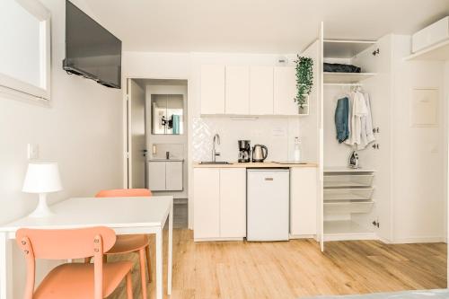 une cuisine avec des armoires blanches et une table et des chaises dans l'établissement Résidence inner center Courbevoie, à Courbevoie