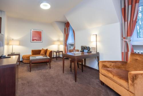 a living room with a couch and a table at Fletcher Waldhotel Nordrhein-Westfalen in Heiligenhaus