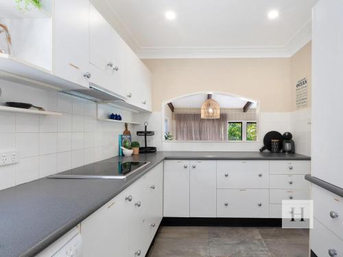 a kitchen with white cabinets and a black counter top at The Place in Summerland Point