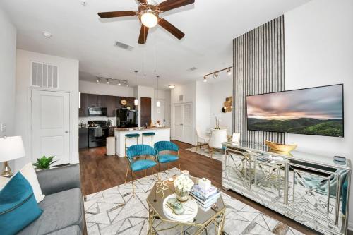 a living room with a ceiling fan and blue chairs at The Alexan* Walk to NRG* TX Med Center* Downtown in Houston
