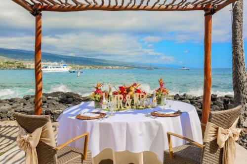 a table with a white table cloth and flowers on a beach at Courtyard by Marriott King Kamehameha's Kona Beach Hotel in Kailua-Kona