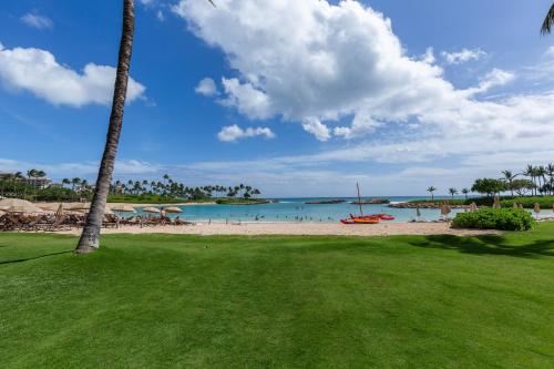 a beach with a palm tree and the ocean at Villa Olina 3-Bedroom Walking Distance From Lagoons 30-day Minimum Vacation Rental in Kapolei