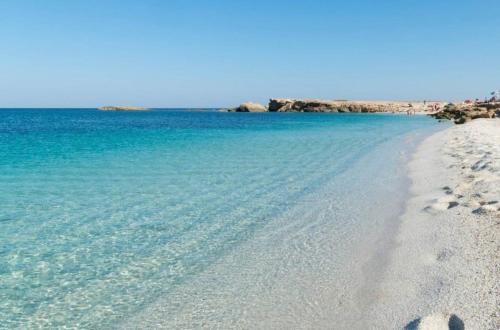 a beach with blue water and footprints in the sand at Casa Futuro - Beautiful sea view with pool in Torre Grande