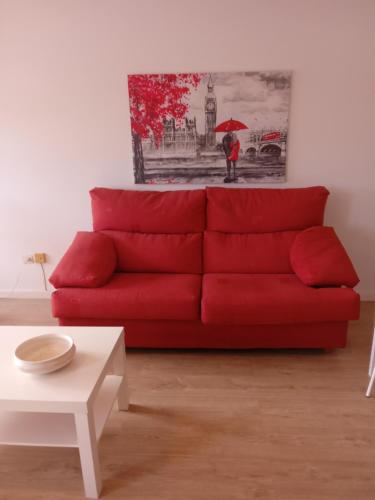 a red couch in a living room with a painting at Paseo de noia in Noya