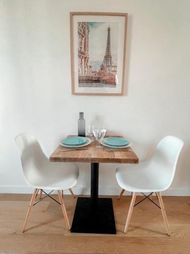 - une table à manger avec 2 chaises blanches et une table avec des assiettes dans l'établissement Studio équipé St cloud proche Paris - La Défense, à Saint-Cloud