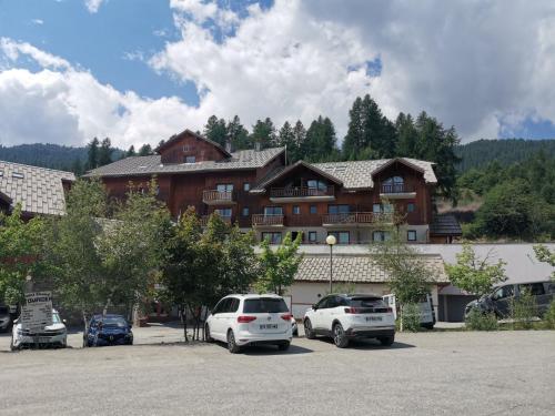 un grand bâtiment avec des voitures garées dans un parking dans l'établissement Appartement 4 personnes Puy Saint Vincent 1800, à Puy-Saint-Vincent