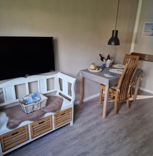 a living room with a table and a flat screen tv at Seekiste in Schleswig