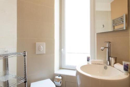 une salle de bain avec un lavabo et des toilettes et une fenêtre dans l'établissement Le Cosy YourHostHelper, à Cannes