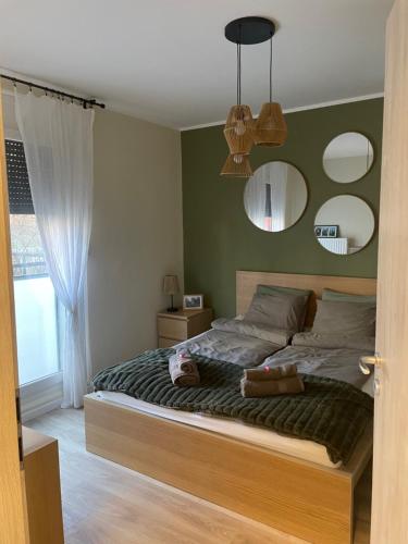 ペーチにあるhellohome apartmanのベッドルーム1室(大型ベッド1台、鏡2つ付)