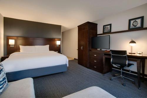 a hotel room with a bed and a desk and a television at Courtyard Worcester in Worcester