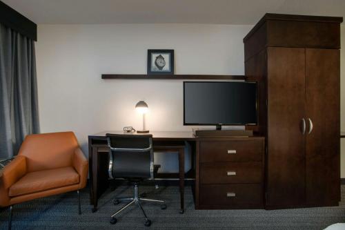a room with a desk with a television and a chair at Courtyard Worcester in Worcester