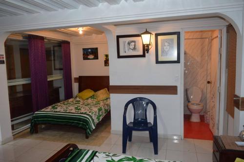 a bedroom with a bed and a chair and a toilet at Hostal las margaritas in Pasto
