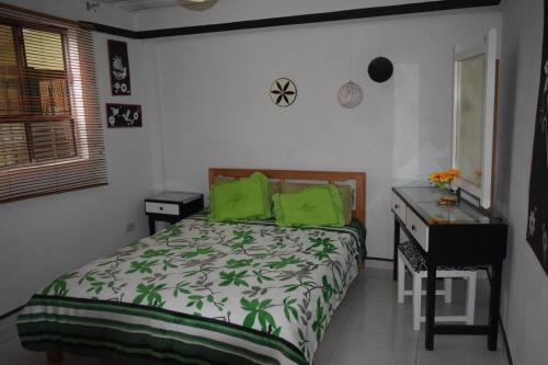 a bedroom with a bed with green pillows and a desk at Hostal las margaritas in Pasto