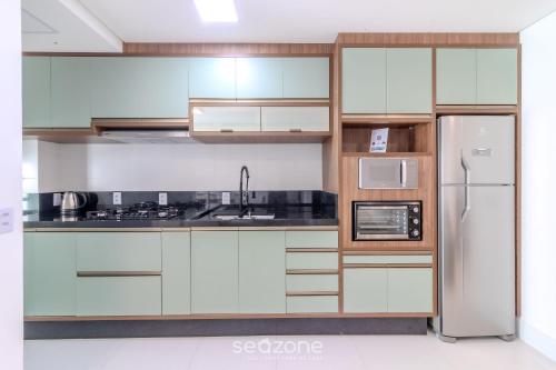a kitchen with white cabinets and a refrigerator at Condomínio a beira-mar c/ piscina - SHC in Piçarras
