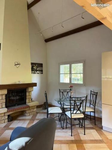 une salle à manger avec une table et une cheminée dans l'établissement Maison cosy avec piscine à Liffol-le-Grand, 42 m², à Liffol-le-Grand