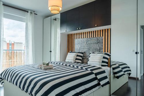 deux lits avec des draps rayés dans une chambre avec une fenêtre dans l'établissement Les ailes du vent - 10min Paris - Parking, à Montreuil