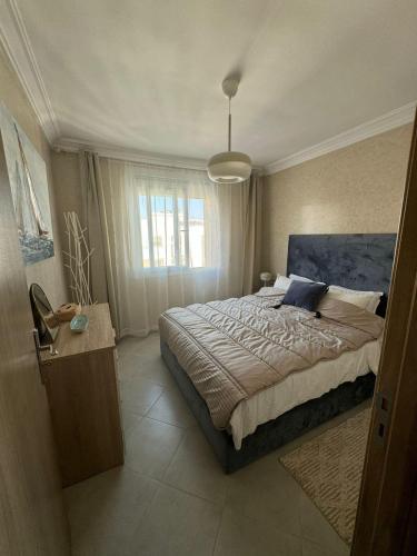 a bedroom with a large bed and a large window at Darkoum Apartment Anza in Agadir