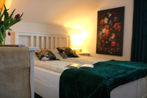 a bed with a green blanket and two slippers on it at Skandi Apartament in Nowa Ruda