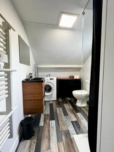 une salle de bain avec machine à laver et toilettes dans l'établissement La Belle Escale, à Ver-sur-Mer