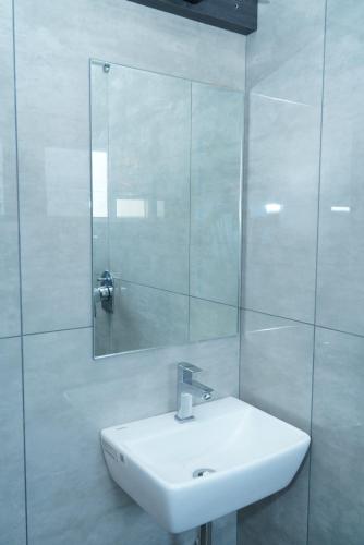 a white bathroom with a sink and a mirror at TPK Residency in Thanjāvūr