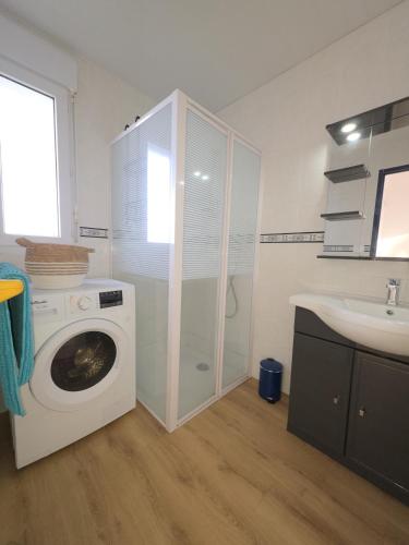 une salle de bain avec une machine à laver et un lavabo dans l'établissement Charmante maison avec accès direct à la plage et vue mer incroyable, à Plouguerneau