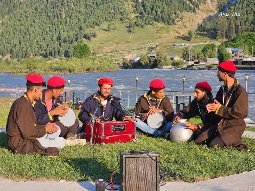 a group of men sitting in the grass with drums at Gurez valley camping site in Wāmpor