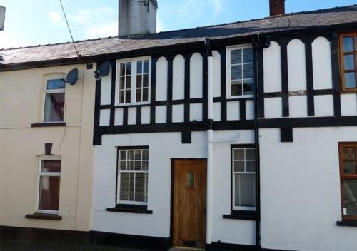 a white and black house with a wooden door at Charming newly renovated 3 bed cottage in Brecon town with private garden & pets welcome in Brecon