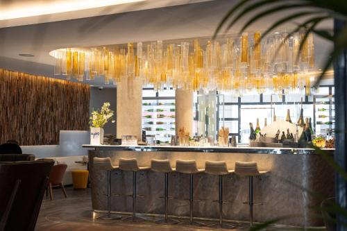 a restaurant with a bar with chairs and chandeliers at Best Western Premier Hotel de la Paix in Reims