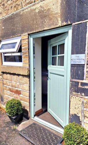 an open door on a brick building with a window at THE OLD WASH KITCHEN - Charming Character Cottage in Holmfirth, Yorkshire in Holmfirth