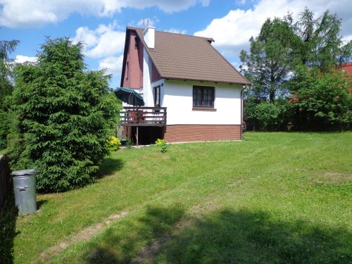 a small white house with a tree in the yard at Domek Letniskowy nad Jeziorem Tumiany in Bartołty Wielkie