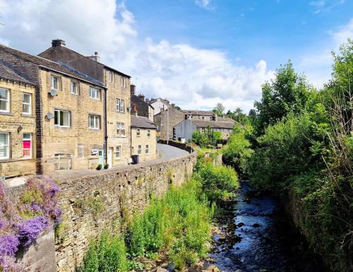 a river in a town with buildings and a street at THE OLD WASH KITCHEN - Charming Character Cottage in Holmfirth, Yorkshire in Holmfirth