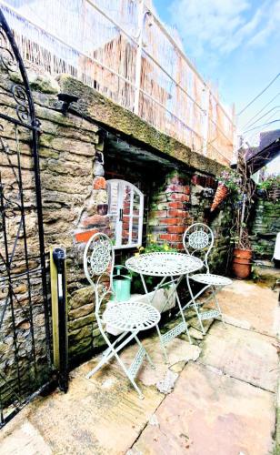 two chairs and a table in front of a building at THE OLD WASH KITCHEN - Charming Character Cottage in Holmfirth, Yorkshire in Holmfirth