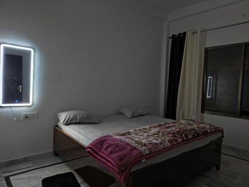 a small bed in a room with a tv on the wall at Siddhi Homestay in Varanasi