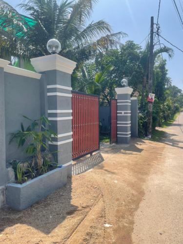 a fence with a red gate next to a street at Cloud9 villa weligama in Weligama