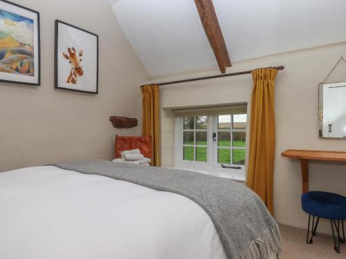a bedroom with a bed and a window at Cherryblossom Cottage in Winkleigh