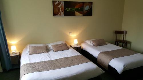 deux lits côte à côte dans une pièce dans l'établissement Hôtel du Commerce, à Ploeuc