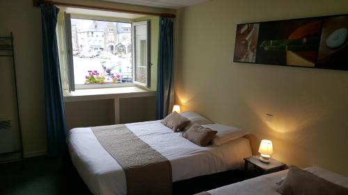 une chambre d'hôtel avec deux lits et une fenêtre dans l'établissement Hôtel du Commerce, à Ploeuc