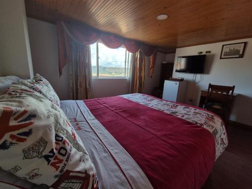 a bedroom with a bed with a red blanket and a window at Hotel Suite Imperial in Tunja
