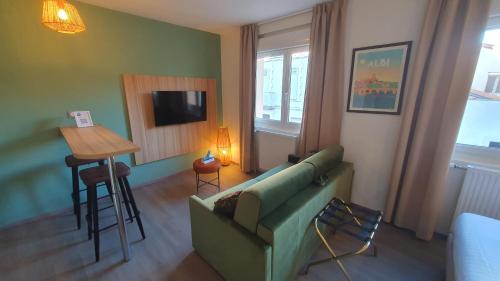 a living room with a green couch and a table at Logis Hôtel - Les Pasteliers in Lavaur
