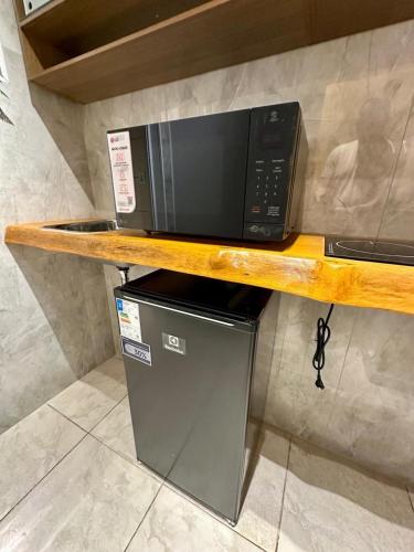 a microwave sitting on top of a wooden shelf at Casa para temporada em Americana SP in Americana