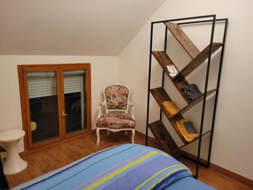 ChécyにあるDuplex dans havre de paix, sur le GR3 proche Loire et Canalのベッドルーム1室(ベッド1台、椅子、棚付)