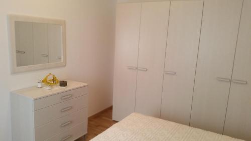 a bedroom with white cabinets and a dresser with a mirror at Apartmani Villa Dragica in Ugljan