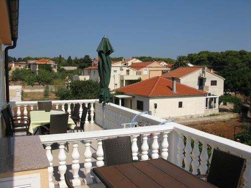 a balcony with a wooden table and a view of a town at Apartmani Villa Dragica in Ugljan