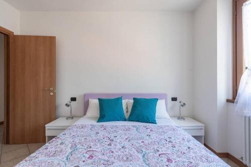 a bedroom with a large bed with blue pillows at Modern apartment with balcony-garage-and pool in Bellano