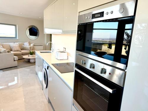 a kitchen with a stove and a living room at Cardiff Skyline Penthouse Apartment Free Parking Sleeps 8 in Cardiff