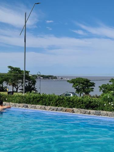a person in a swimming pool with a view of the water at Apart Altos del Virrey in Colonia del Sacramento